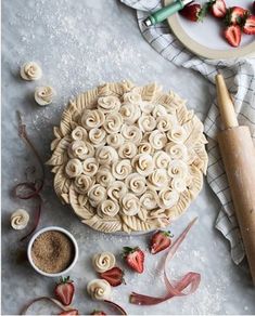 an uncooked pie sitting on top of a table next to sliced strawberries