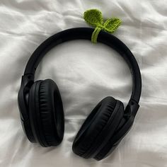 a pair of headphones laying on top of a white sheet with a green leaf