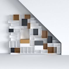 a book shelf with many books on it in front of a white wall and stairs