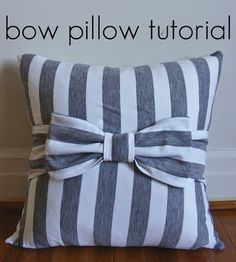 a bow pillow sitting on top of a wooden floor next to a white and gray wall