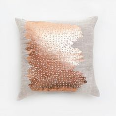 a pillow with gold sequins on the front and back, sitting against a white wall