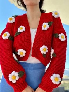 a woman wearing a red cardigan with flowers on it