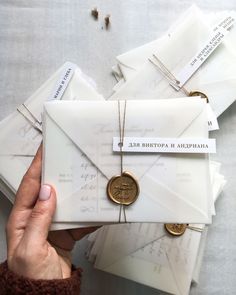 a person holding an envelope with a wax stamp on it and several other letters surrounding it