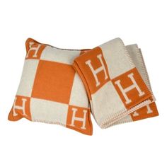 two orange and white pillows sitting on top of each other