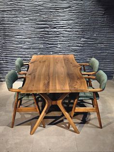 a wooden table with six chairs around it in front of a wall made of stone