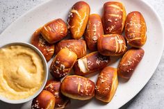 a white plate topped with hot dogs covered in mustard next to a bowl of dip