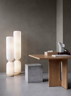 two tall white vases sitting on top of a wooden table