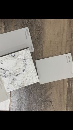 some white and grey paint on top of a wooden floor next to two different boxes