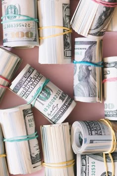 rolls of money tied with twine on pink background