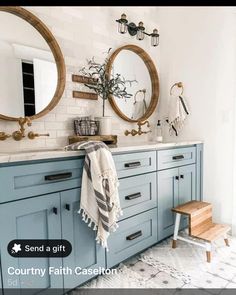 a bathroom with two round mirrors and blue cabinets