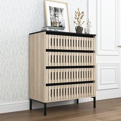 a wooden cabinet with black trim on the top and bottom, in front of a white wall