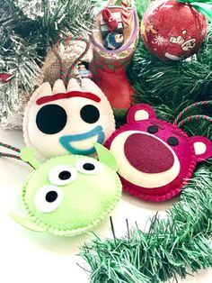 three christmas ornaments sitting next to each other on top of a green pine tree branch