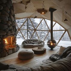 Discover the ultimate cozy retreat in this Nordic igloo house interior, featuring a large geometric window with snowy views, a rustic stone fireplace, plush seating, and a modern hanging stove. Perfect for those seeking a serene and stylish winter hideaway. Igloo Interior, Domo Aesthetic, Nordic Fireplace, Igloo House, Smart Houses, Rustic Stone Fireplace, Globe Projects, Camp Ground, Holiday Houses