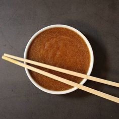 two wooden chopsticks sticking out of a bowl filled with brown sugar and cinnamon