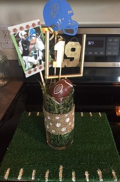 a football themed centerpiece in a glass vase on a green placemat next to an oven