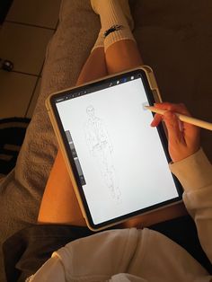 a person sitting on the floor holding an ipad with a pencil in their hand and drawing