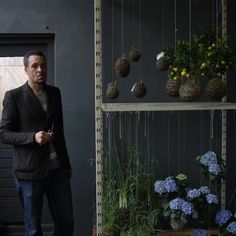 a man standing in front of a shelf filled with plants