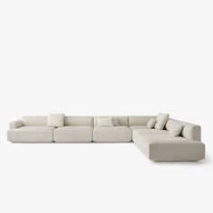 a large sectional couch with pillows on the top and bottom, sitting in front of a white background