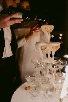 a bride and groom are pouring champagne into wine goblets at their wedding reception