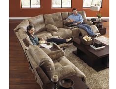 two people laying on couches in a living room with brown carpet and red walls