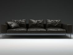 a black leather couch sitting on top of a white floor next to a gray wall