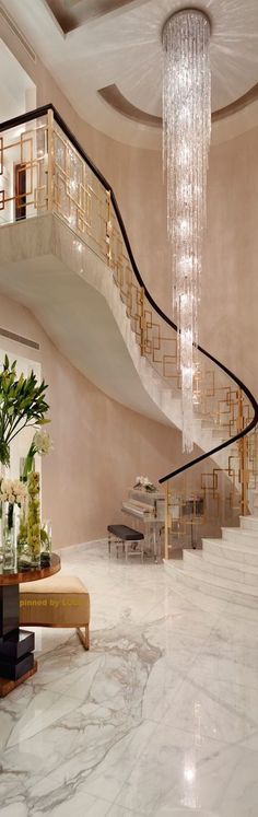 an elegant staircase with chandelier and marble flooring in a living room area