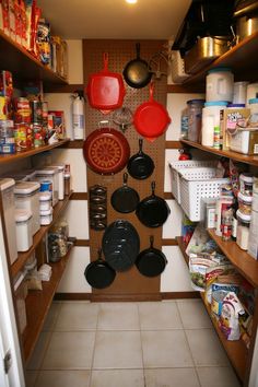 an organized pantry with pots and pans hanging on the wall