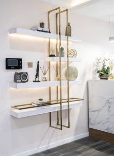 a white and gold shelving unit in the corner of a room with marble counter tops