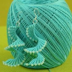 a ball of yarn with two birds on it and some beads hanging from the end