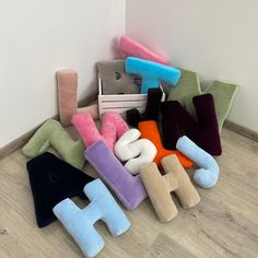 a pile of stuffed toys sitting on top of a wooden floor next to a wall