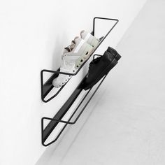 a pair of shoes is hanging on a wall with a black shelf holding two pairs of sneakers