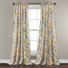 a yellow and blue floral curtain hanging in front of a window with a chair next to it