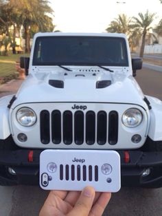 a person holding up a white jeep license plate