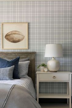 a bed room with a neatly made bed and a painting on the wall above it