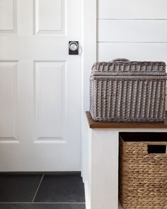 a wicker basket sitting on top of a wooden table next to a white door