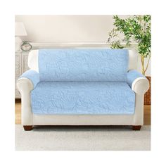 a couch covered in a blue and white quilted cover next to a potted plant