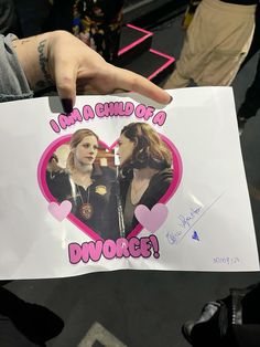 a person holding up a sign with two girls on it