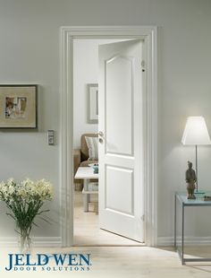 an open door leading to a living room with flowers in the vase on the table