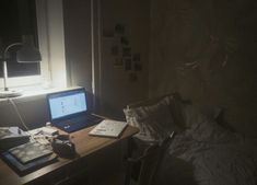 an open laptop computer sitting on top of a wooden desk next to a lamp and window