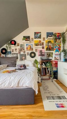 a bed sitting under a slanted ceiling next to a wall with pictures on it