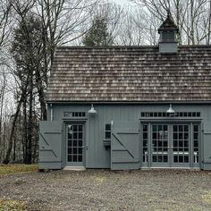 a gray building with two windows and a brown roof