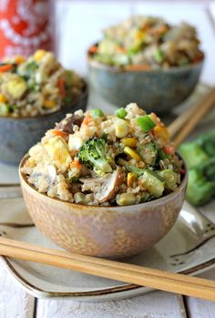 a bowl filled with rice and vegetables next to chopsticks on top of a plate