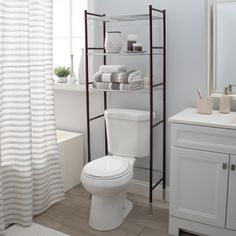 a white toilet sitting in a bathroom next to a bathtub and shower curtain with striped curtains