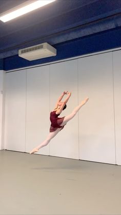 a woman is doing a dance move in an empty room