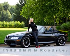 a woman standing next to a black sports car