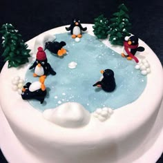 there is a cake decorated with penguins in the water