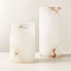 two marble vases sitting next to each other on a white counter top, one with a brown vein