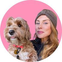 a woman holding a dog in front of a pink circle with the image of her