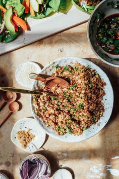 a bowl filled with rice and vegetables next to other bowls full of food on top of a wooden table