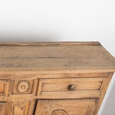 an old wooden dresser with carvings on the doors and drawers is displayed against a white wall